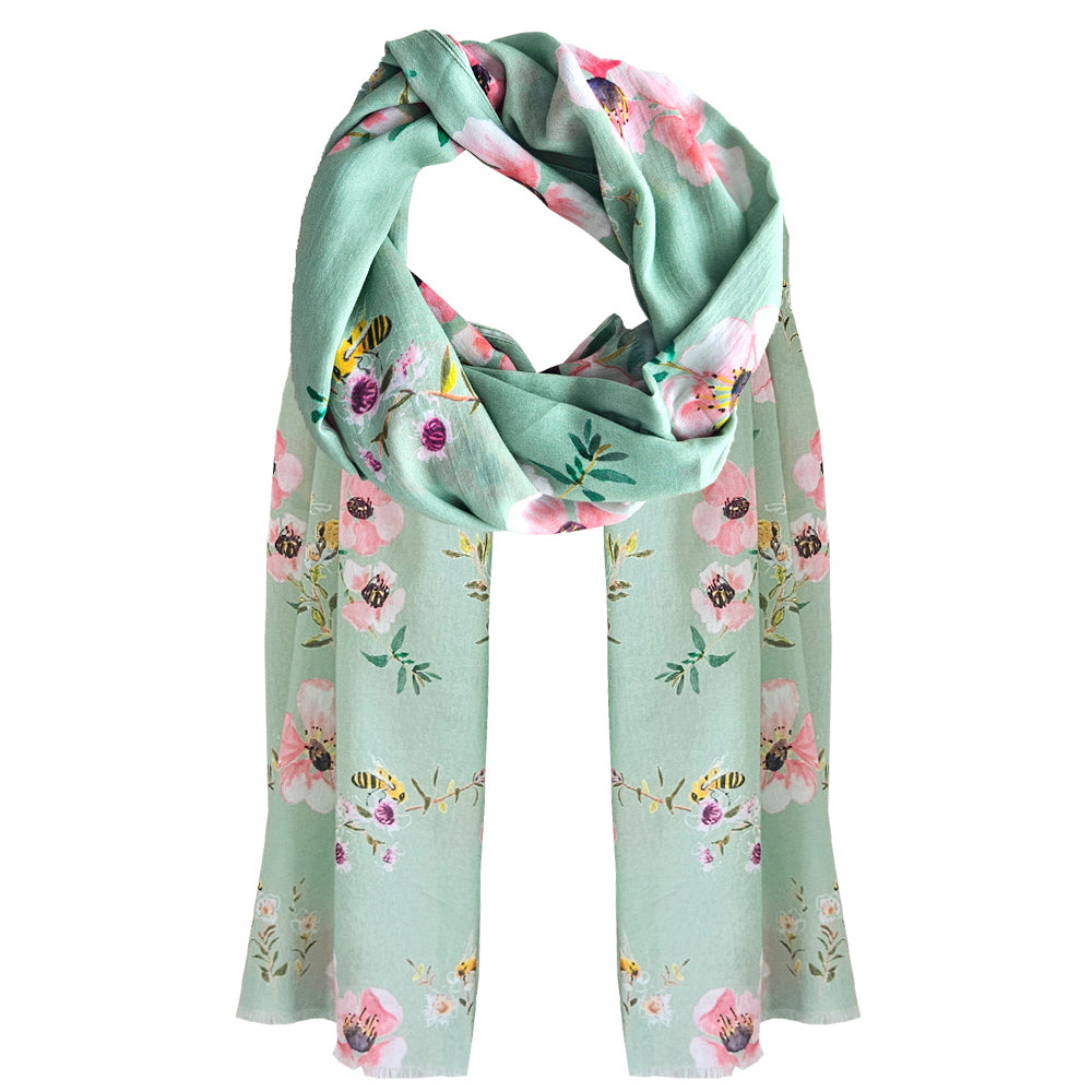 A sage green coloured cotton scarf with manuka flowers and bees printed over the scarf.