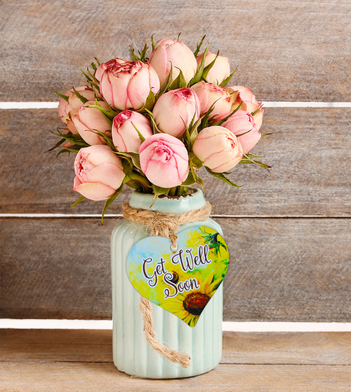 A wooden heart gift tag with a daisy illustration and get well soon message written on across the middle.