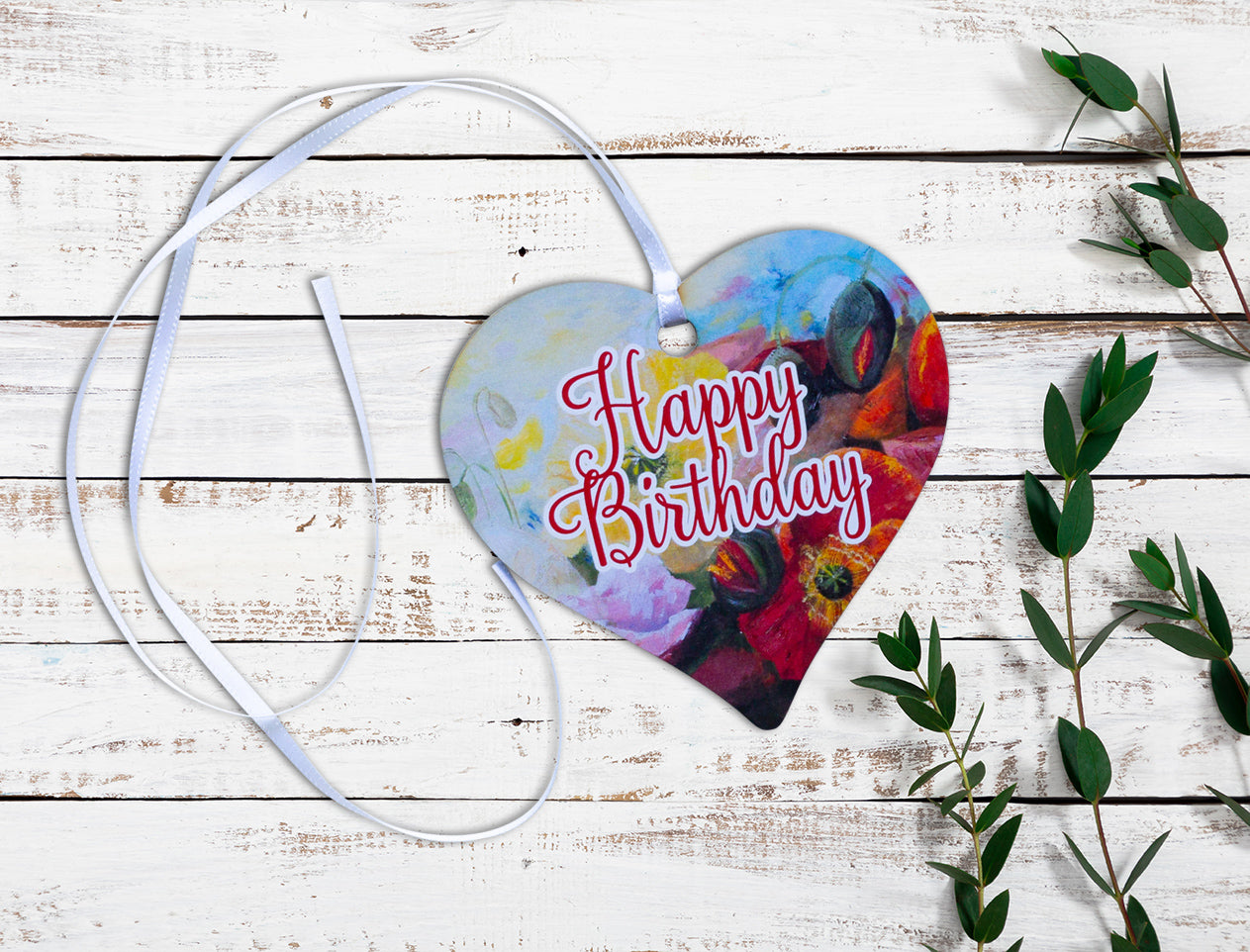 A wooden heart tag with a happy birthday message and floral design.