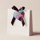 A wooden heart tag with a happy birthday message and floral design.
