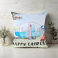 Decorative pillow with a camper design and 'Happy Camper' text on a wooden surface.