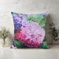 Decorative pillow with floral design on a wooden surface with plants.
