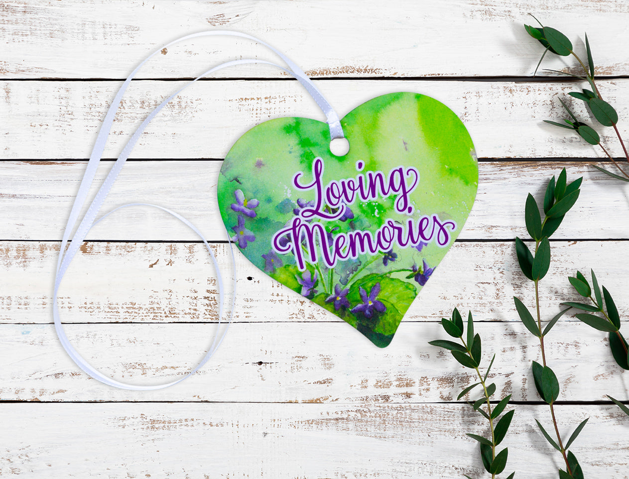 A wooden heart tag with a floral background in greens and purples with a message saying 'Loving Memories'.