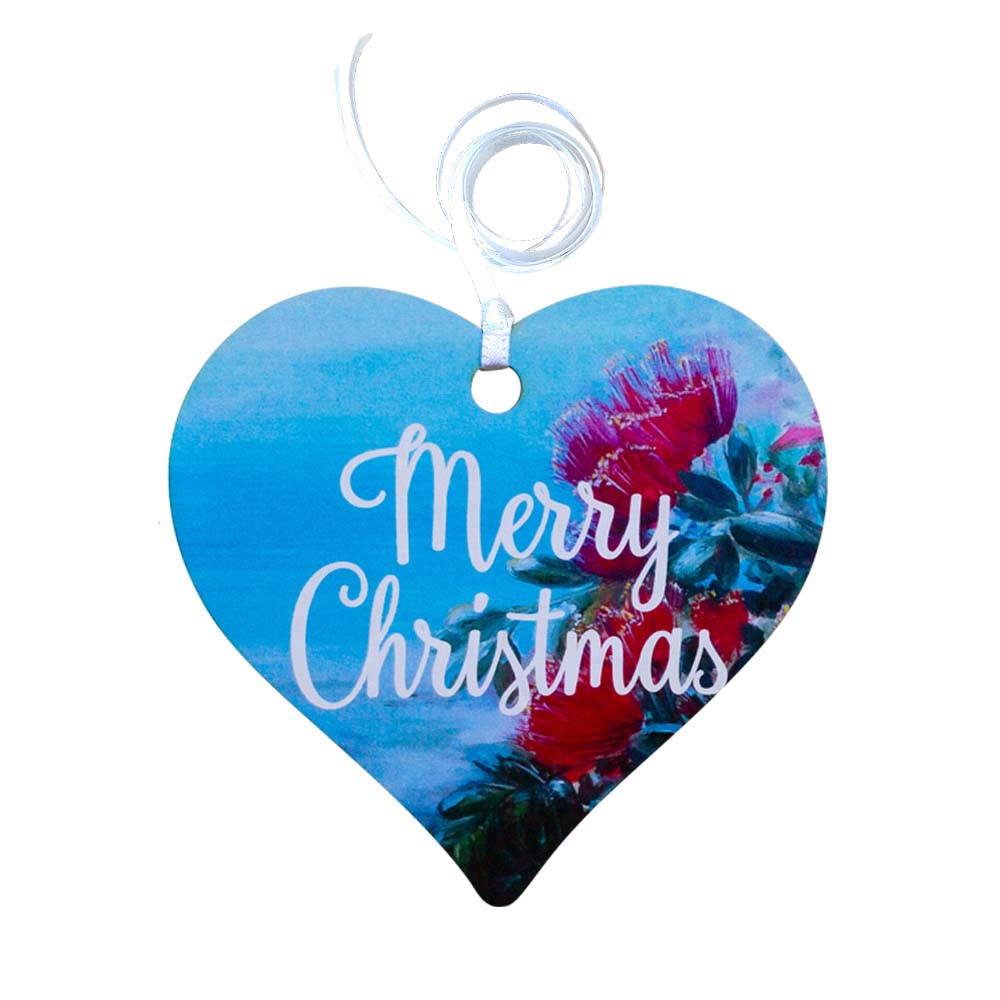 A wooden heart tag with a pohutukawa design and merry christmas written on the front.