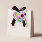 A wooden heart tag with the message 'Mum' and a floral wreath design.