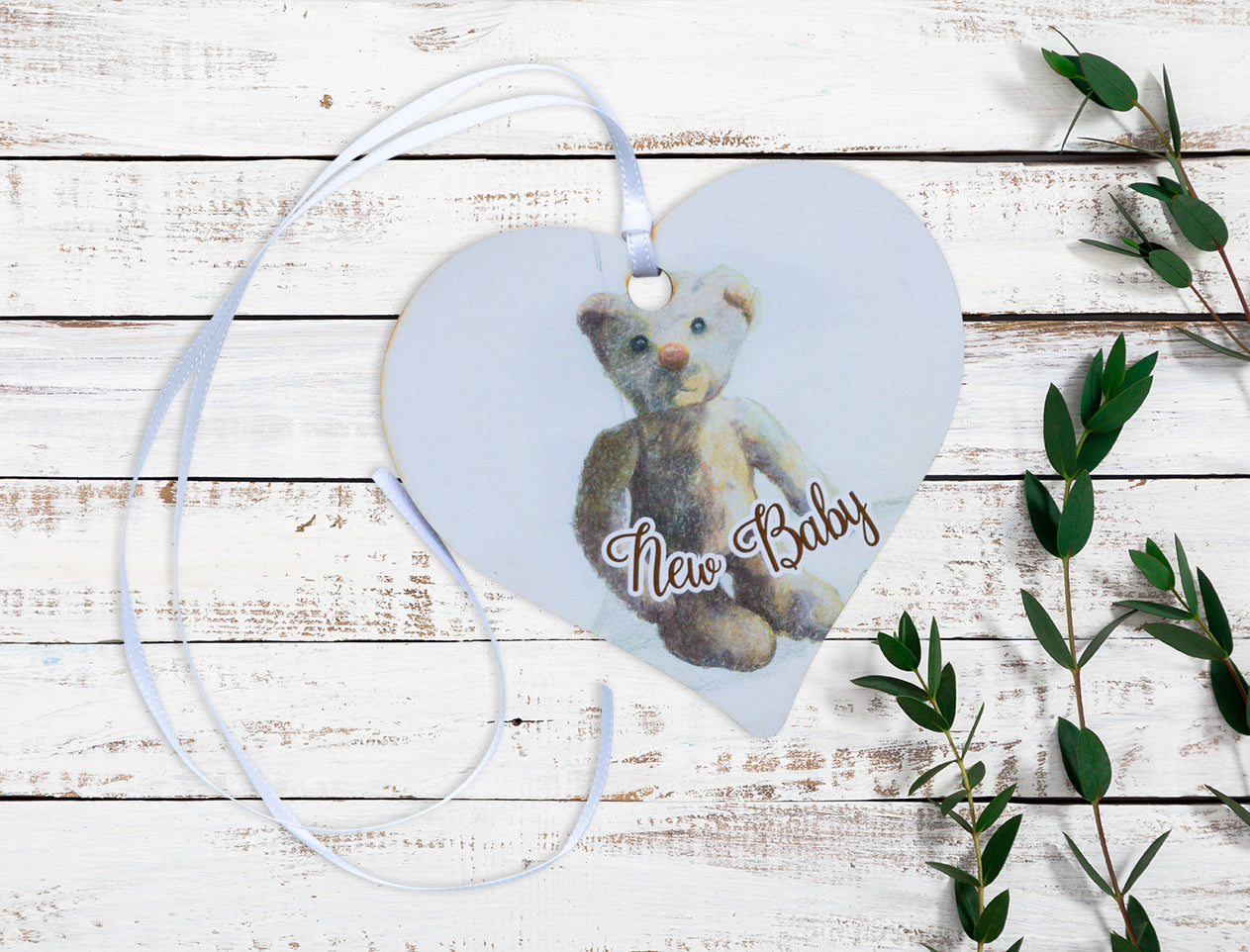 A wooden gift tag with a teddy bear illustration and the words New Baby written at the bottom. 