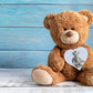 A wooden gift tag with a teddy bear illustration and the words New Baby written at the bottom. 