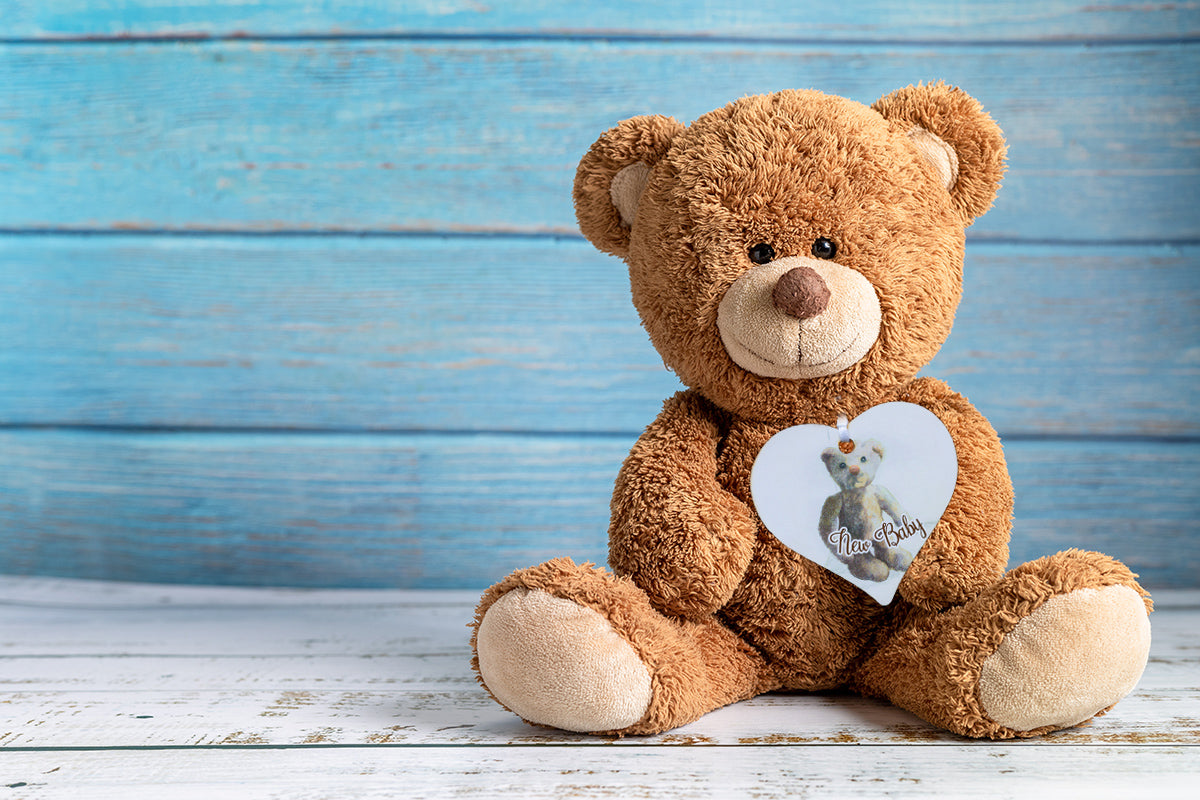 A wooden gift tag with a teddy bear illustration and the words New Baby written at the bottom. 