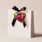 A wooden heart tag with the message 'with love' and a red rose design.